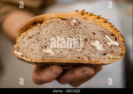 Una fetta di pane con noce. Un panettiere contiene pane appena sfornato. Messa a fuoco morbida Foto Stock