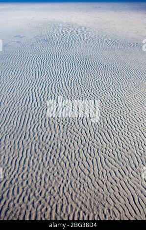 Il movimento naturale delle onde e del vento formò modelli nella sabbia piatta della spiaggia sulla costa dello stato di Washington. Foto Stock