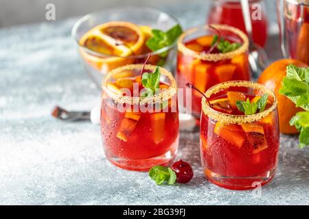 Tre bicchieri di cocktail italiano aperol spritz con fette di arancia e ingredienti su un tavolo in pietra grigio chiaro. Drink estivo, sangria fatta in casa, cocktail Foto Stock