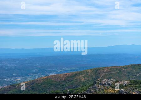 Vista dalla cima del Caramulo montagne oltre i Estrela montagne, rocce granitiche e macchia mediterranea in Portogallo Foto Stock