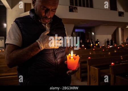 Beirut, Libano, 17 aprile 2020. La gente tiene le candele durante un servizio della chiesa del Venerdì Santo. Alcuni membri della congregazione della chiesa di Sant'Efrem hanno rotto il coprifuoco per osservare il tradizionale servizio del Venerdì Santo durante la chiusura del coronavirus in Libano. Negli anni precedenti, parteciperanno fino a 1500 partecipanti, quest'anno più guardati tramite live streaming su facebook. Elizabeth Fitt Foto Stock