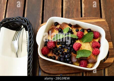 Pancake con formaggio casolare al centro e salsa di frutti di bosco. Gustosa colazione su sfondo di legno. Dolce dessert di frittelle con lampone. Foto Stock