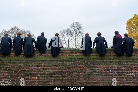 Eton, Windsor, Berkshire, Regno Unito. 20 novembre 2010. I ragazzi dell'Eton College si siedono in cima a un muro alto costruito nel 1717 accanto ai campi da gioco dell'Eton College mentre osservano i loro compagni di scuola competere nel Wall Game. Il primo gioco da parete registrato fu nel 1766. L'Eton College è una scuola pubblica a pagamento, frequentata da molti politici britannici, tra cui Boris Johnson e David Cameron. Anche il Principe William e il Principe Harry frequentarono l'Eton College. Credito: Maureen McLean/Alamy Foto Stock