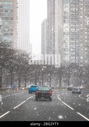 Auto che attraversano la città nella neve, Chicago, Illinois, USA Foto Stock