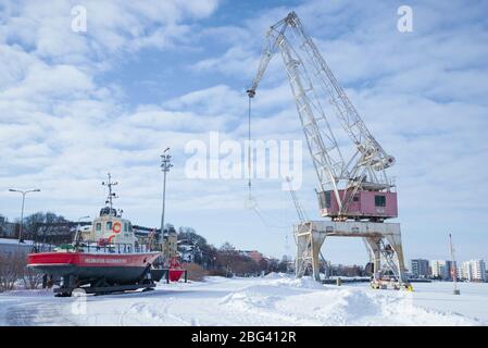 KOTKA, FINLANDIA - 25 FEBBRAIO 2018: Motoscafo e gru portuale sul lungomare della città nel pomeriggio di febbraio Foto Stock