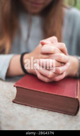 adolescente ragazza che prega, mani sulla bibbia. concetto di fede e speranza. Foto Stock