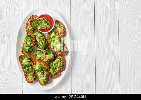 Il broccoli fonde i sandwich di verdure a vista di broccoli arrostiti e cipolla fritta con il provolone fuso sulla parte superiore con il ketchup su un piatto bianco su un Foto Stock