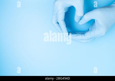 Mani del medico con guanti che fanno la figura del cuore Foto Stock