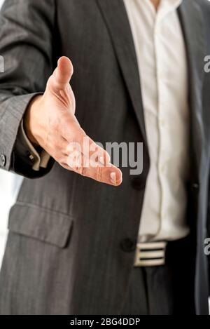 Primo piano giovane uomo d'affari in abito nero che ti offre una mano in Handshake Gesture alla fotocamera. Foto Stock