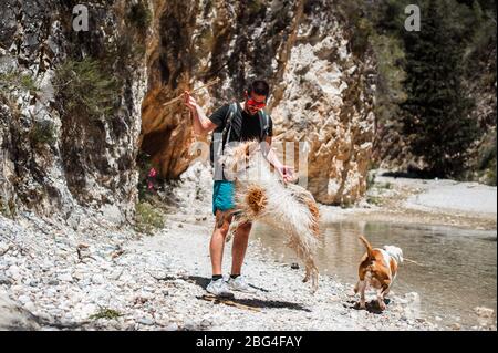 Giovane uomo che gioca con i cani al canyon del fiume Foto Stock