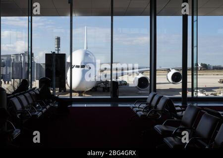 Aereo di linea a lungo raggio che aspetta di fronte ad un aeroporto visto dall'interno del terminal, da una sala d'attesa dove la gente di solito aspetta per la propria auto Foto Stock