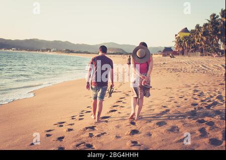 Uomo e donna che camminano lungo la spiaggia al tramonto in Messico Foto Stock