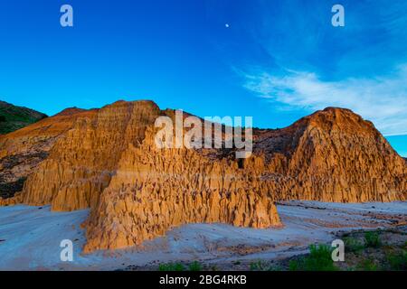 Ultima luce del sole sulle montagne di argilla, mentre la luna sorge sulla Cathedral Gorge, Nevada Foto Stock