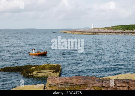 Un pescatore sostenibile di ciglia o aragosta nella sua piccola barca di aragosta di legno vicino Ullapool gettando le sue trappole. Foto Stock