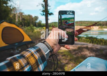 uomo che prende la foto del telefono delle donne che posano sull'amaca Foto Stock