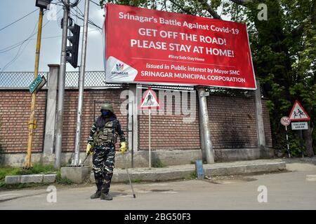 Un trooper paramilitare si alza in piedi sulla strada durante un blocco nazionale.il blocco imposto per aiutare a combattere la diffusione di pandemia di coronavirus nella valle del Kashmir è stato esteso fino al 03 maggio 2020. Il numero di casi COVID-19 in Jammu e Kashmir è salito a 354, mentre altre quattro persone hanno provato positivo per il virus, ha detto lunedì. Foto Stock