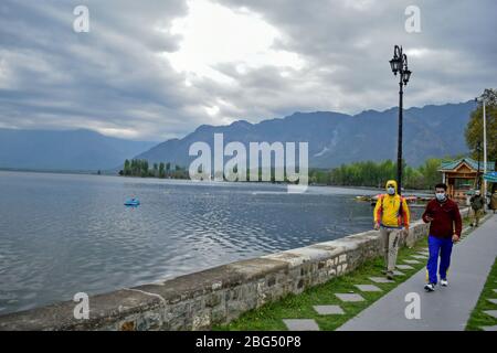 I residenti che indossano maschere facciali protettive camminano lungo la riva del lago dal durante un blocco nazionale.il blocco imposto per aiutare a combattere la diffusione di pandemia di coronavirus nella valle del Kashmir è stato esteso fino al 03 maggio 2020. Il numero di casi COVID-19 in Jammu e Kashmir è salito a 354, mentre altre quattro persone hanno provato positivo per il virus, ha detto lunedì. Foto Stock