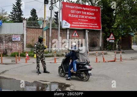 Un trooper paramilitare arresta un motociclista durante un blocco nazionale.il blocco imposto per aiutare a combattere la diffusione di pandemia di coronavirus nella valle del Kashmir è stato esteso fino al 03 maggio 2020. Il numero di casi COVID-19 in Jammu e Kashmir è salito a 354, mentre altre quattro persone hanno provato positivo per il virus, ha detto lunedì. Foto Stock