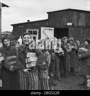 Documentario sulla seconda guerra mondiale. I prigionieri del campo di concentramento di Bergen-Belsen raccolgono allegramente le razioni di pane dopo la loro liberazione da parte delle forze britanniche nell'aprile 1945. Foto Stock