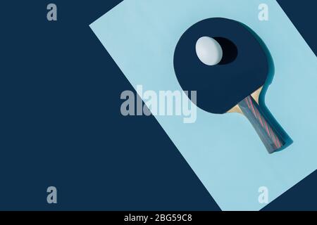 Il semestre sportivo è iniziato. Un uovo bianco giace su una racchetta blu da ping pong. Un pezzo di carta è adagiato su uno sfondo blu. Foto Stock