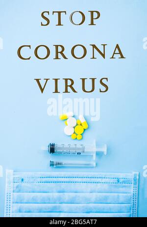 Pillole, capsule, compresse, siringa e ago gialli su sfondo blu con copyspace. Stop concetto di coronavirus. Proteggetevi. Foto Stock