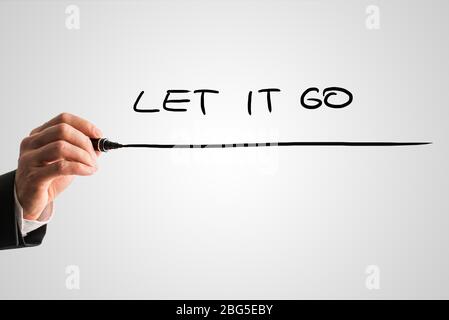 Uomo che scrive le parole - Let IT Go - con un pennarello nero da dietro uno schermo virtuale o interfaccia su uno sfondo grigio chiaro con copyspace, chiudere Foto Stock