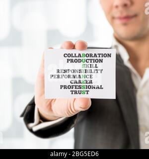 Businessman che tiene un piccolo white card concettuale con testo aziendale e altre parole correlate, enfatizzando collaborazione, produzione, abilità, Responsibi Foto Stock