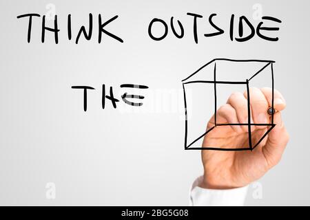 Mano maschile scrivere su uno schermo virtuale un messaggio creativo inspirazionale che invita a pensare fuori dalla scatola. Foto Stock