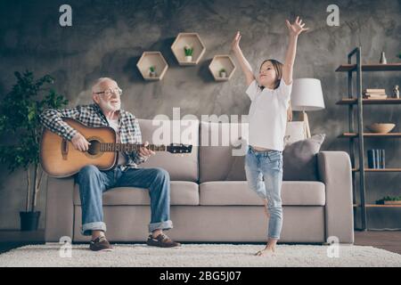 Foto di divertente vecchio nonno poco bella nipote che suona la chitarra ballare avendo divertimento legame rimanere a casa quarantena sicurezza interni moderni Foto Stock