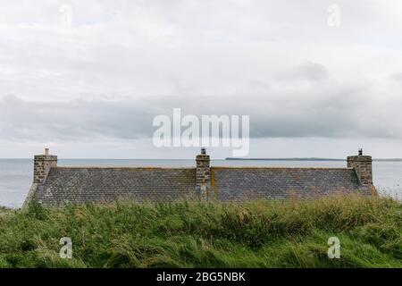 Vista sul mare sul tetto di una casa che si affaccia sul porto storico del piccolo villaggio di Keiss a Caithness, Scozia. Foto Stock