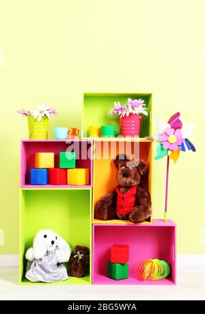 Scaffali luminosi di colori diversi con giocattoli sullo sfondo della parete Foto Stock