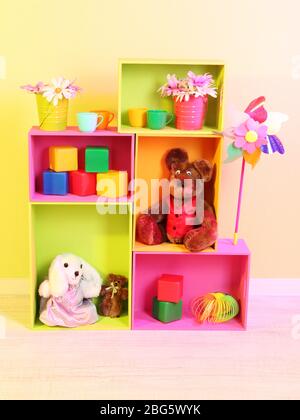 Scaffali luminosi di colori diversi con giocattoli sullo sfondo della parete Foto Stock