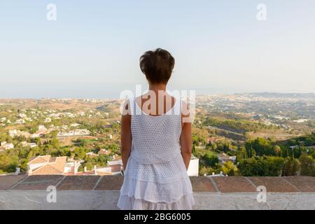 Vista posteriore di donna turistica matura che guarda il bellissimo scenario del villaggio di Mijas in Spagna Foto Stock