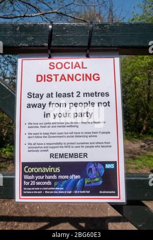 NHS Coronavirus/CoVid-19 segnale di informazione pubblica che promuove il distanziamento sociale messo in su all'entrata ad un parco a Hounslow, Londra occidentale, Regno Unito. Foto Stock