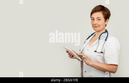 Ritratto di una dottoressa utilizzando il suo tablet digitale. Medico femminile che usa la compressa e verifica con analisi su un'interfaccia virtuale. Medicina. Scienza medica e biotecnologia. Foto Stock
