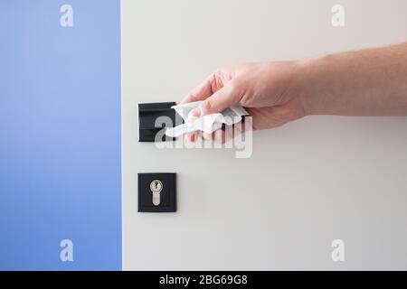 Primo piano della maniglia della porta per la pulizia manuale con tubo bagnato disinfettante, disinfettante le superfici domestiche contro virus o batteri. Raccomandazioni e. Foto Stock