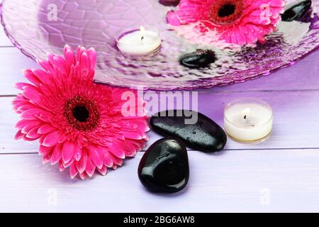 Pietre termali, splendidi fiori di gerbera e candele sull'acqua Foto Stock