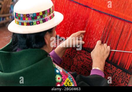 Donna indigena in abiti tradizionali che tessono un colorato tessuto Jalq'a a Sucre, Bolivia. Foto Stock