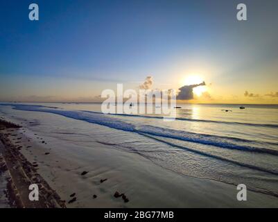 Bellissima alba sulla spiaggia di Diani sull'Oceano Indiano. E' una mattinata di sole in Kenya, Africa. Ci sono piccole barche in legno sull'acqua. Foto Stock