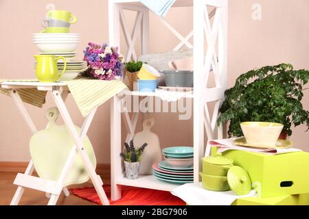 Bella mobilia bianca con stoviglie e decor, su sfondo a parete colorato Foto Stock