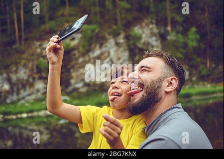 Divertimento. Padre esempio di nobile umano. Prendere selfie con il figlio. Bambino che corre sulle spalle dei papà. Felicità essere padre di ragazzo. Foto Stock