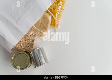 Vari alimenti in scatola, pasta, riso e cereali crudi su un tavolo in sacchetto di carta con spazio per copia Foto Stock