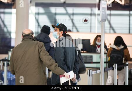 Toronto, Canada. 20 aprile 2020. I viaggiatori che indossano maschere facciali si allineano per effettuare il check in durante l'epidemia COVID-19 all'Aeroporto Internazionale Pearson di Toronto, Canada, il 20 aprile 2020. Il Ministro dei Trasporti canadese Marc Garneau ha annunciato il 17 aprile una nuova misura che avrà effetto il 20 aprile, richiedendo a tutti i passeggeri delle compagnie aeree di coprire le loro bocche e nasi con una maschera non medica o con altre coperture facciali presso i checkpoint di screening aeroportuali. Credit: Zou Zheng/Xinhua/Alamy Live News Foto Stock