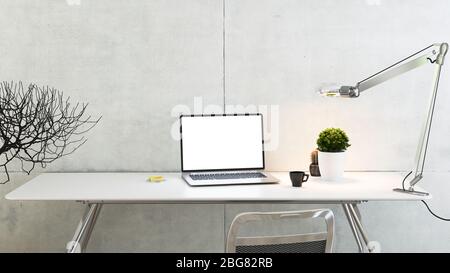 Laptop sul tavolo dell'ufficio con impianto, lampada da scrivania, tazza da caffè e parete in cemento con rendering 3D Foto Stock