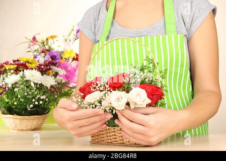 Fiorista fa bouquet di fiori in vimini cesto Foto Stock