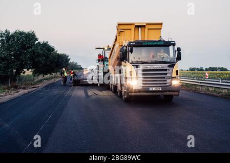 lavoratori edili su strada che utilizzano la pavimentazione. manutenzione autostradale, asfaltatrice che stendono nuovo asfalto o bitume durante la costruzione di autostrade Foto Stock