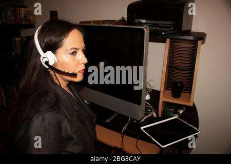 Home Office messicano businesswoman donna occhi color miele con un archetto posto sulla testa per ascoltare e parlare mentre risponde a una chiamata in remoto utilizzando Foto Stock