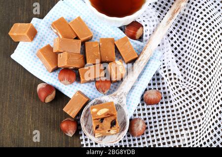 Molti toffee in cucchiaio e tazza di tè su tovaglioli su tavola di legno Foto Stock