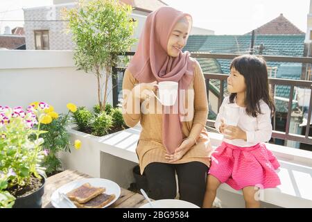 madre e figlia musulmana gustare la loro colazione in giardino Foto Stock