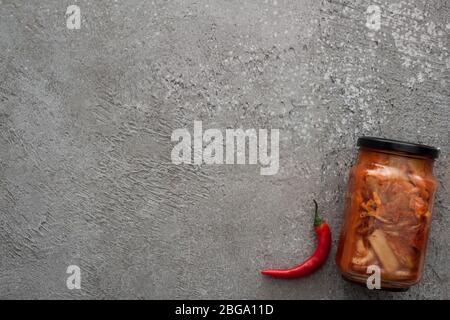 vista dall'alto del peperoncino rosso e del vaso kimchi su fondo grigio in cemento Foto Stock